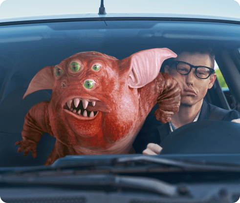 Creature elbowing a man who is driving in the face