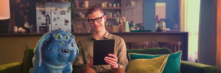 Creature sitting next to a man on his tablet with the VELSIPITY (etrasimod) VELSIPITYForMe