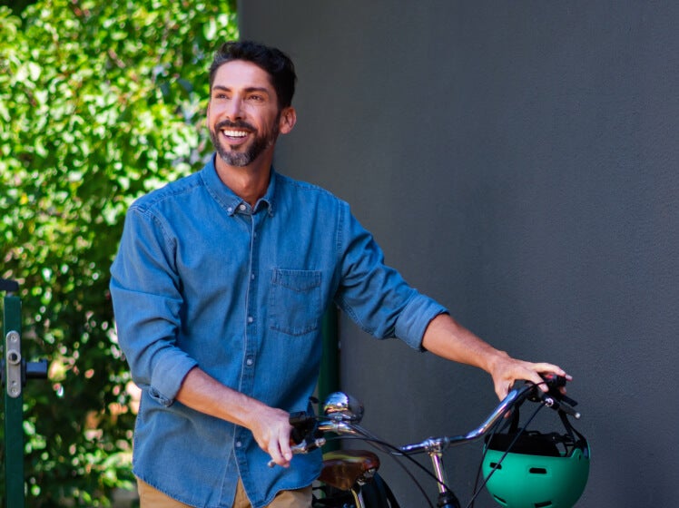 Smiling man walking next to a bicycle