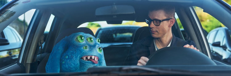 Creature and a man driving with one another in a car